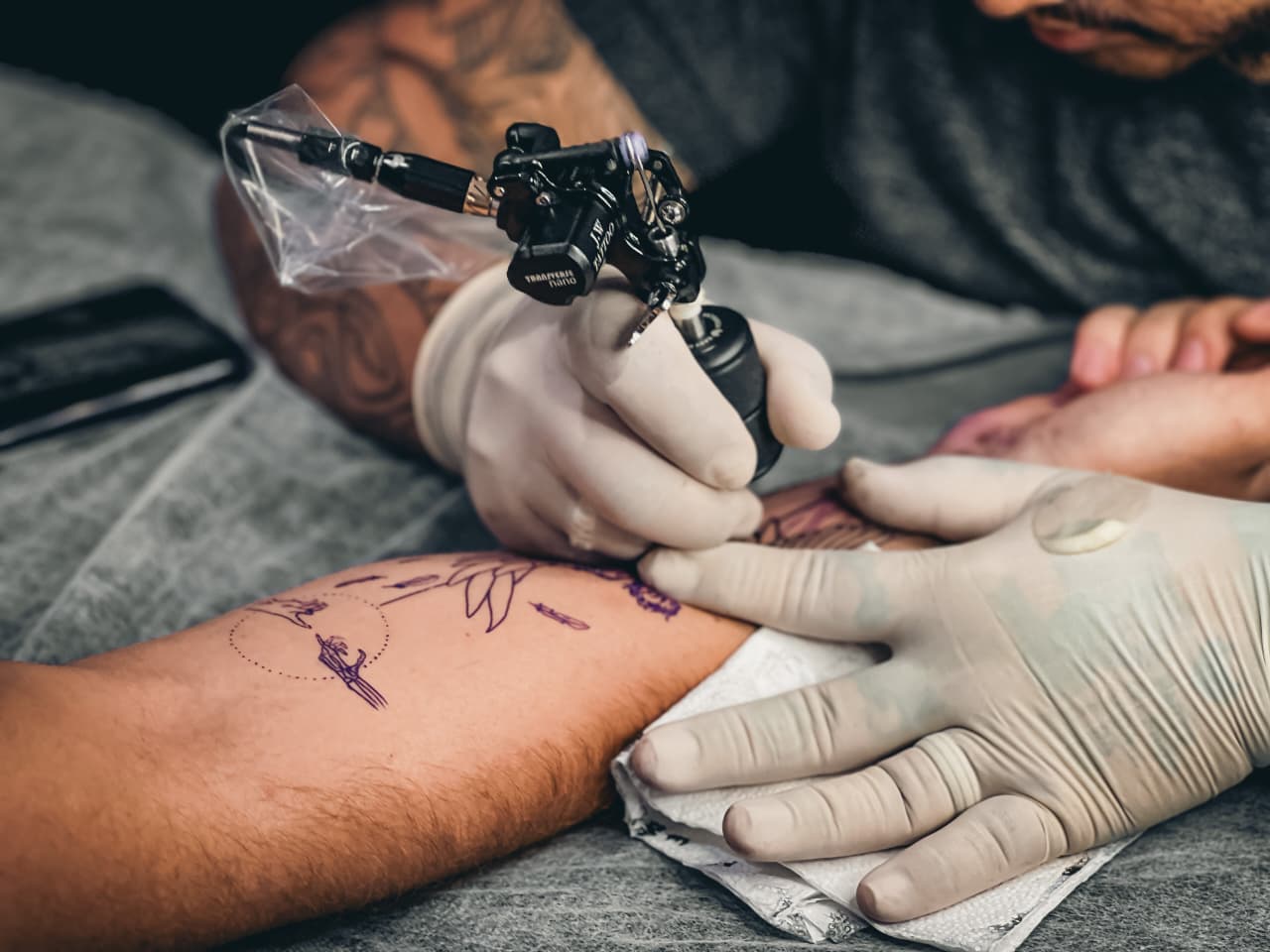 Close da máquina de tatuagem durante atendimento